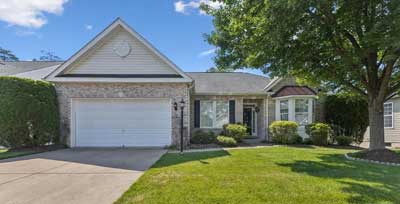 Light brick large home with paved drive and bay window